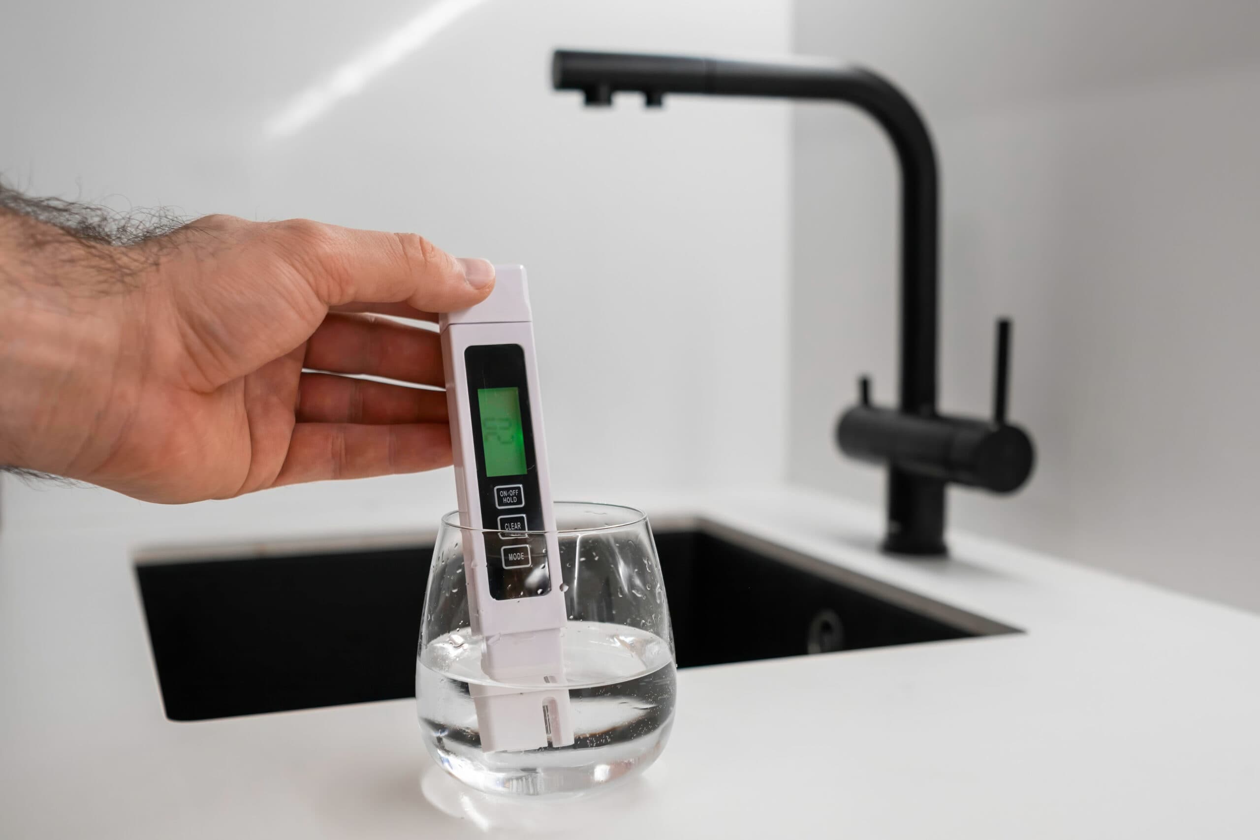Hand die een TDS-meter in een glas water houdt